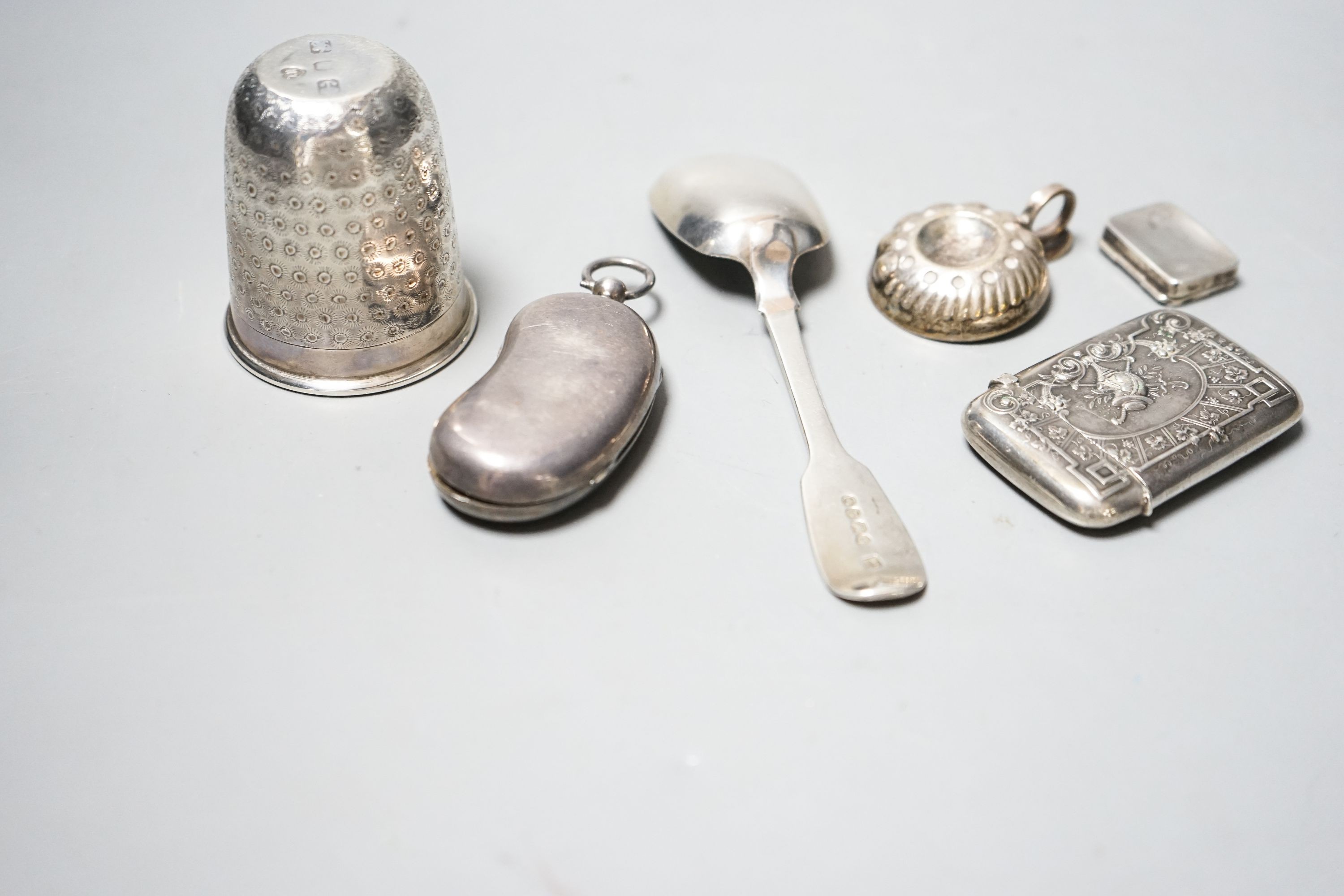 A George V silver twin sovereign kidney shaped case, 65mm, a silver spoon, silver tot , silver pill box, a German 800 vesta case and a plated small taste vin.